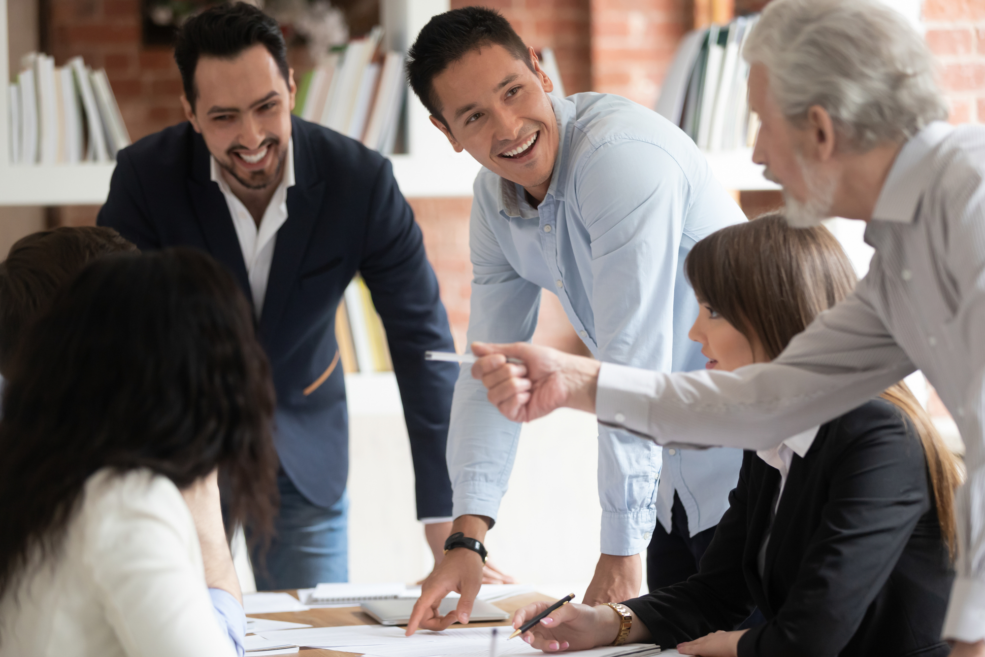 Happy diverse business team young and old employees talking brainstorming on project paperwork gather at conference table